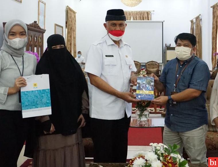 Gubernur Sumbar, Mahyeldi Ansharulah, saat menerima buku 'Nyala Asa di Tengah Badai Corona' yang ditulis oleh mantan General Manager PT PLN Unit Induk Wilayah (UIW) Sumatera Barat (Sumbar). IST