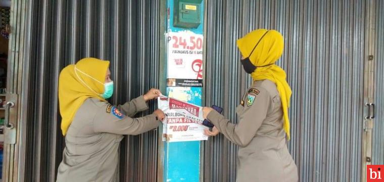 Banpol puteri Satuan Polisi Pamong Praja (Satpol PP) Kota Padang Panjang menertibkan iklan rokok yang terpasang di warung-warung, Selasa (9/3).